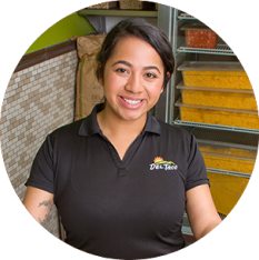 Portrait photo of a Del Taco Shift Manager. She is holding food prep container and wears a branded Del Taco polo.